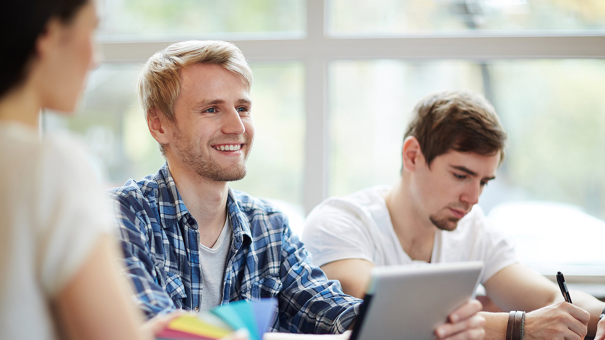 Studierende im dualen Studium arbeiten gemeinsam mit Tablet und Notizen bei Autohaus Fischer.