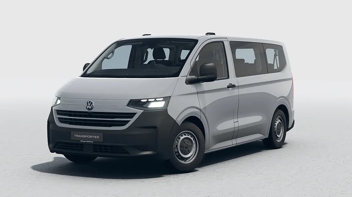 Grauer VW Transporter in schräger Frontansicht vor hellem Studiohintergrund.