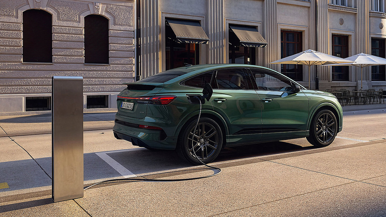 Grüner Audi Q4 Sportback e-tron Elektro-SUV beim Laden an einer Ladestation