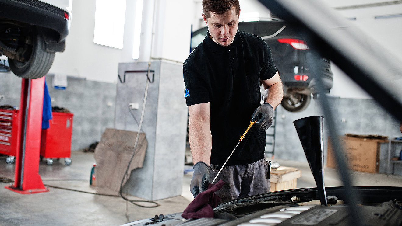 Mechaniker prüft ein Fahrzeug in der Werkstatt im Rahmen von HU und AU Service.