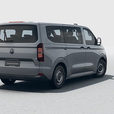 Grauer VW Transporter in der Heckansicht schräg von hinten auf hellem Untergrund.