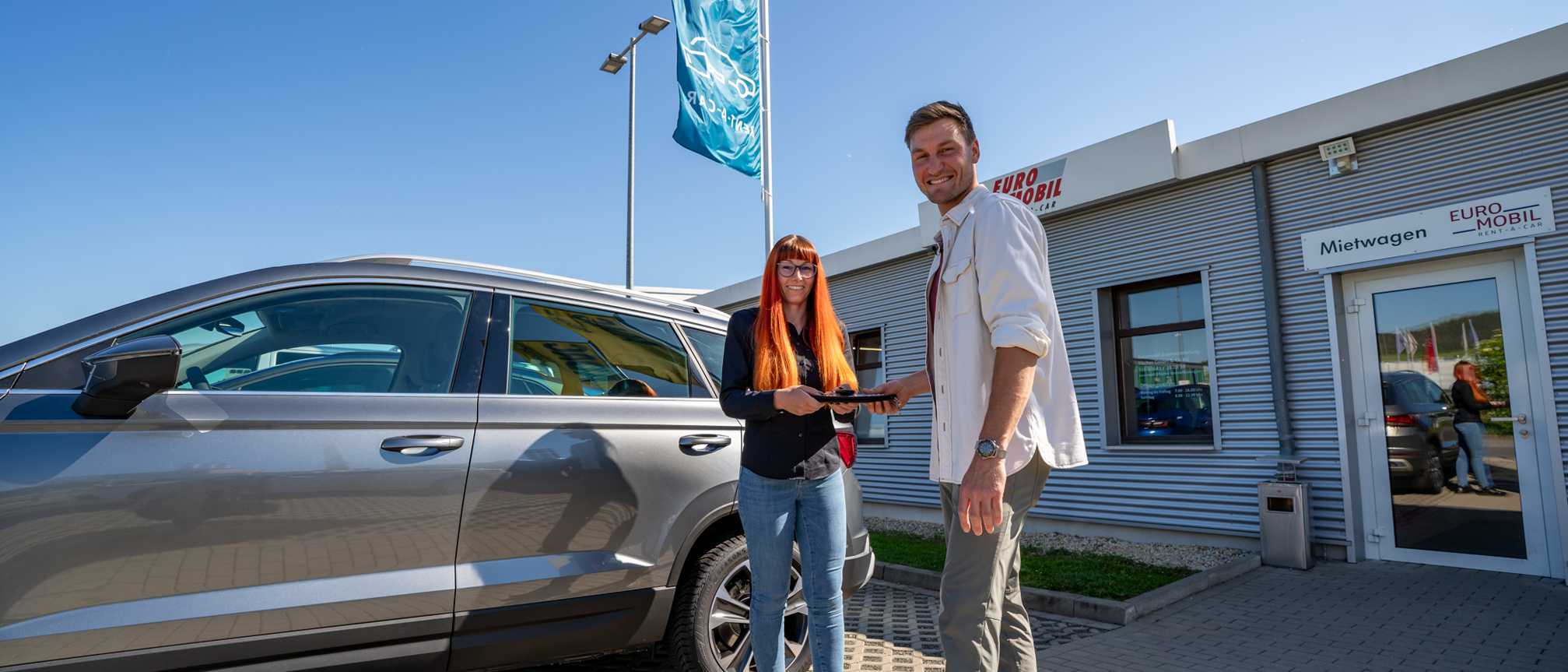 Schluesseluebergabe bei der Rent-a-Car Autovermietung in Jena vor einem Mietwagen