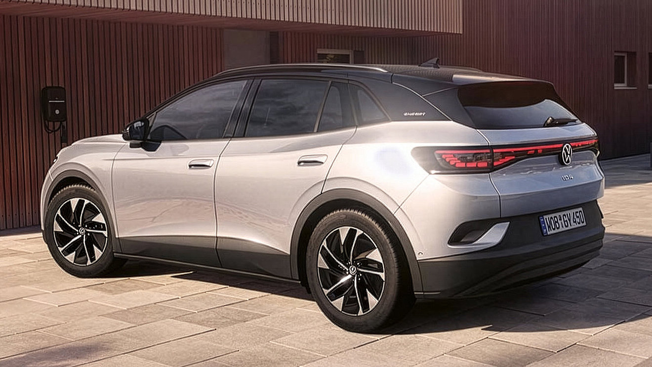 Silberner VW ID.4 Elektro-SUV in schräger Heckansicht vor einem modernen Gebäude mit Holzfassade.