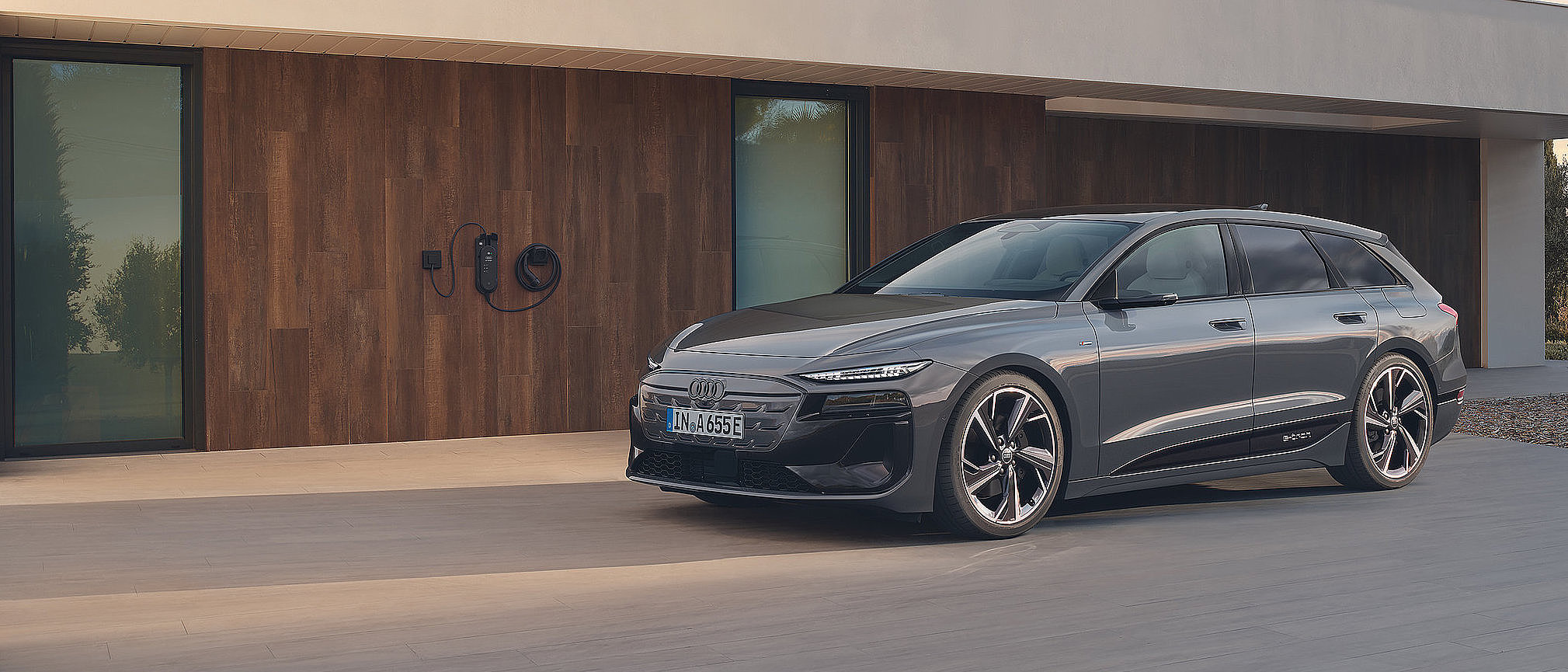 Audi A6 e-tron Avant vor moderner Hausfassade mit Wallbox
