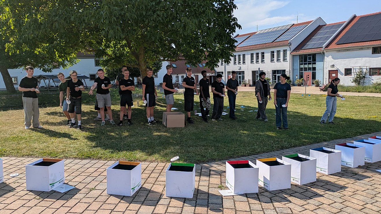 Die neuen Azubis im ersten Lehrjahr vom Autohaus Fischer bei einem Teamspiel im Stehen.