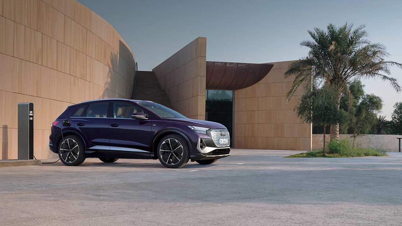 Audi Q4 e-tron als Elektro-SUV vor moderner Architektur und Ladestation