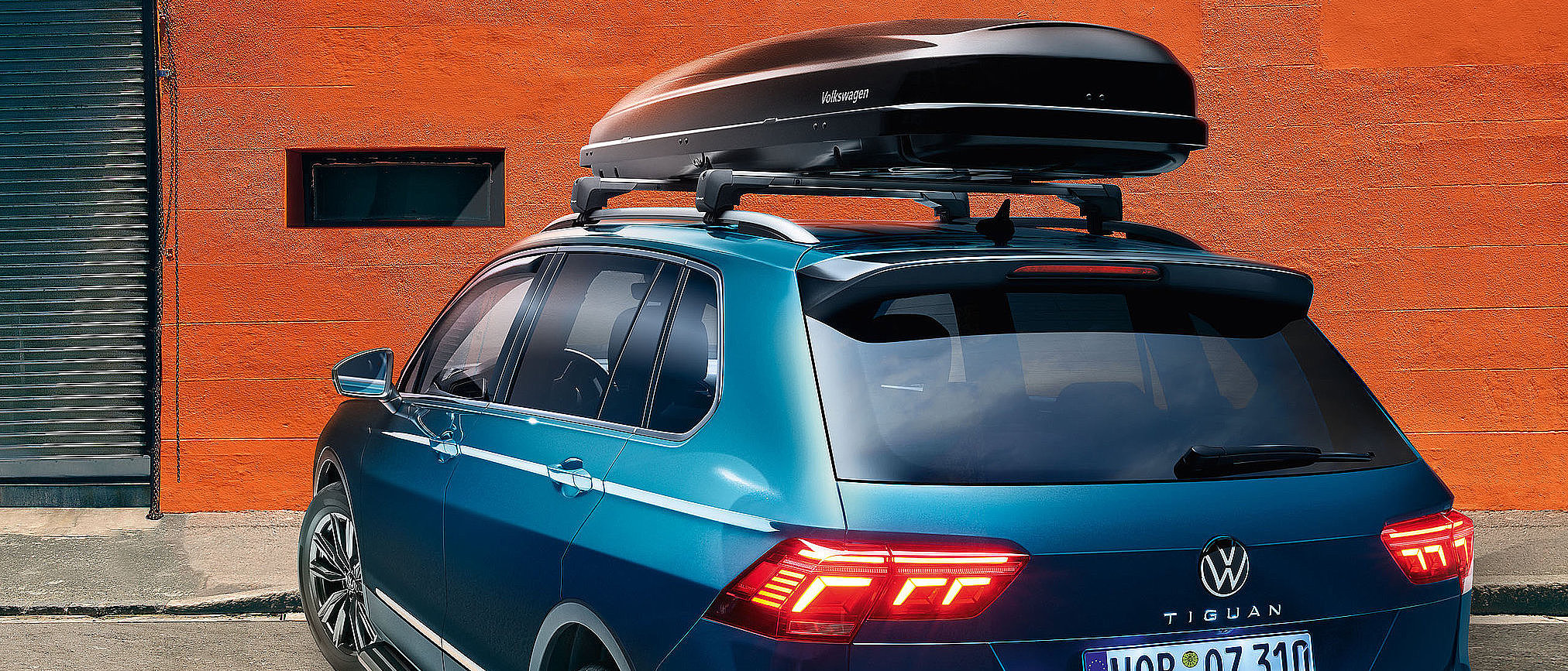 Volkswagen Tiguan mit montierter Dachbox als Mietzubehör für zusätzlichen Stauraum.