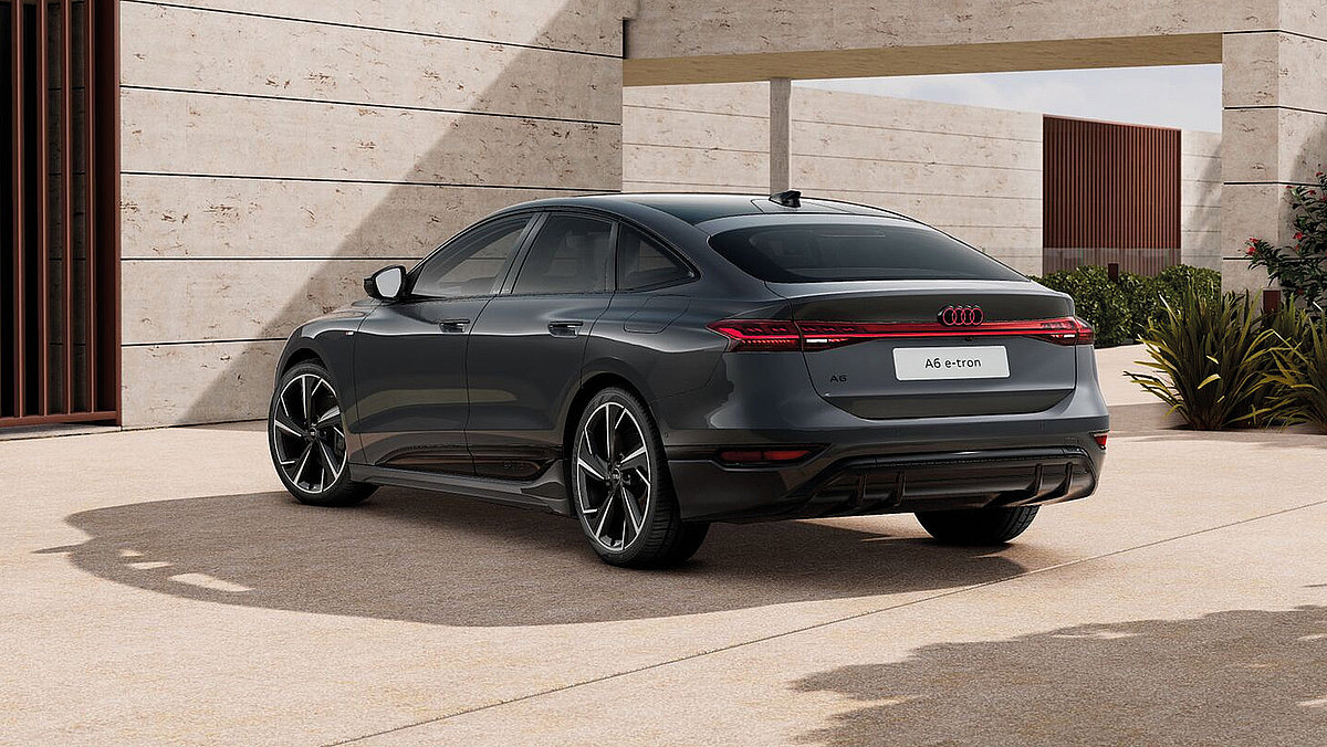 Grauer Audi A6 e-tron in schräger Heckansicht vor moderner Architektur