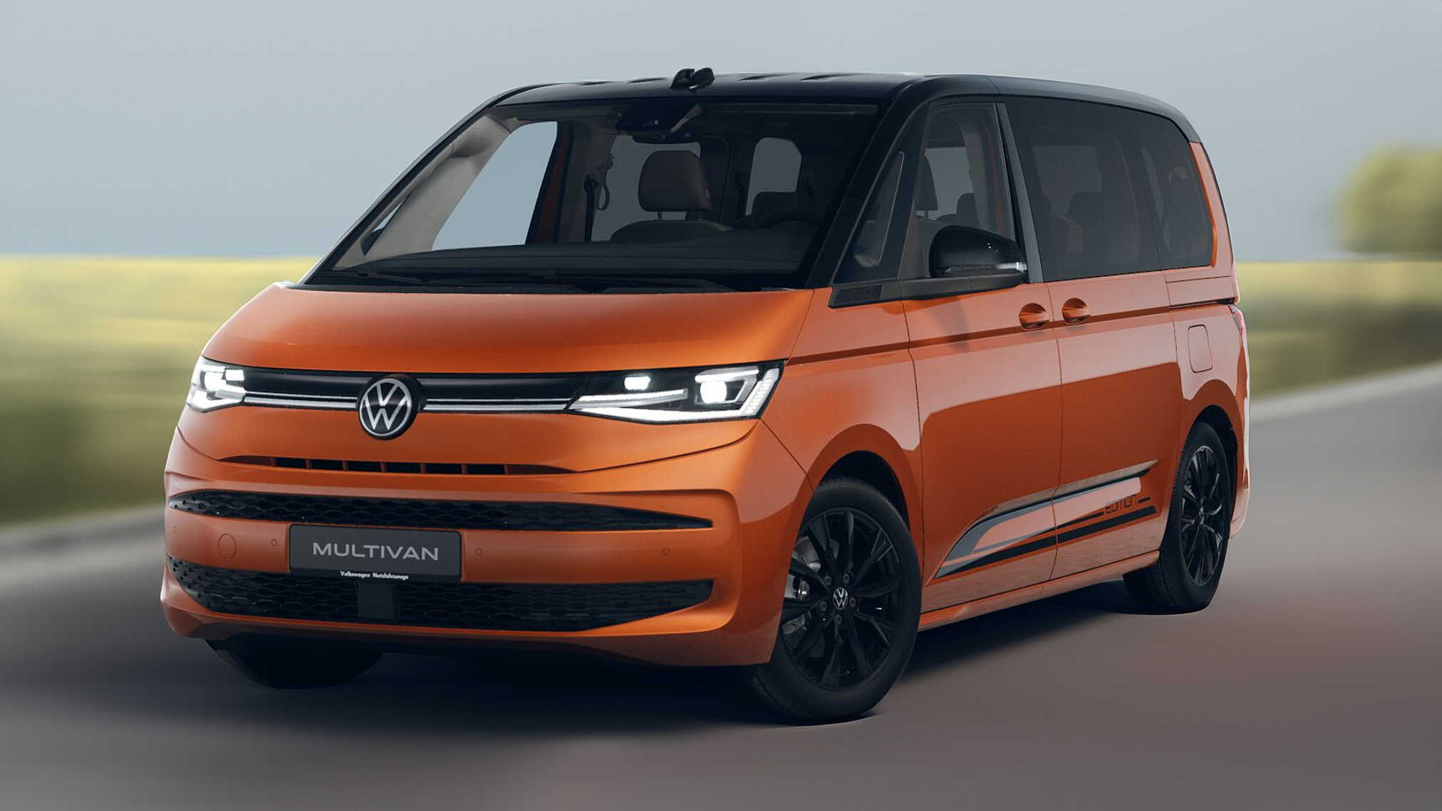 Oranger VW Multivan eHybrid Edition in schräger Frontansicht auf der Straße.