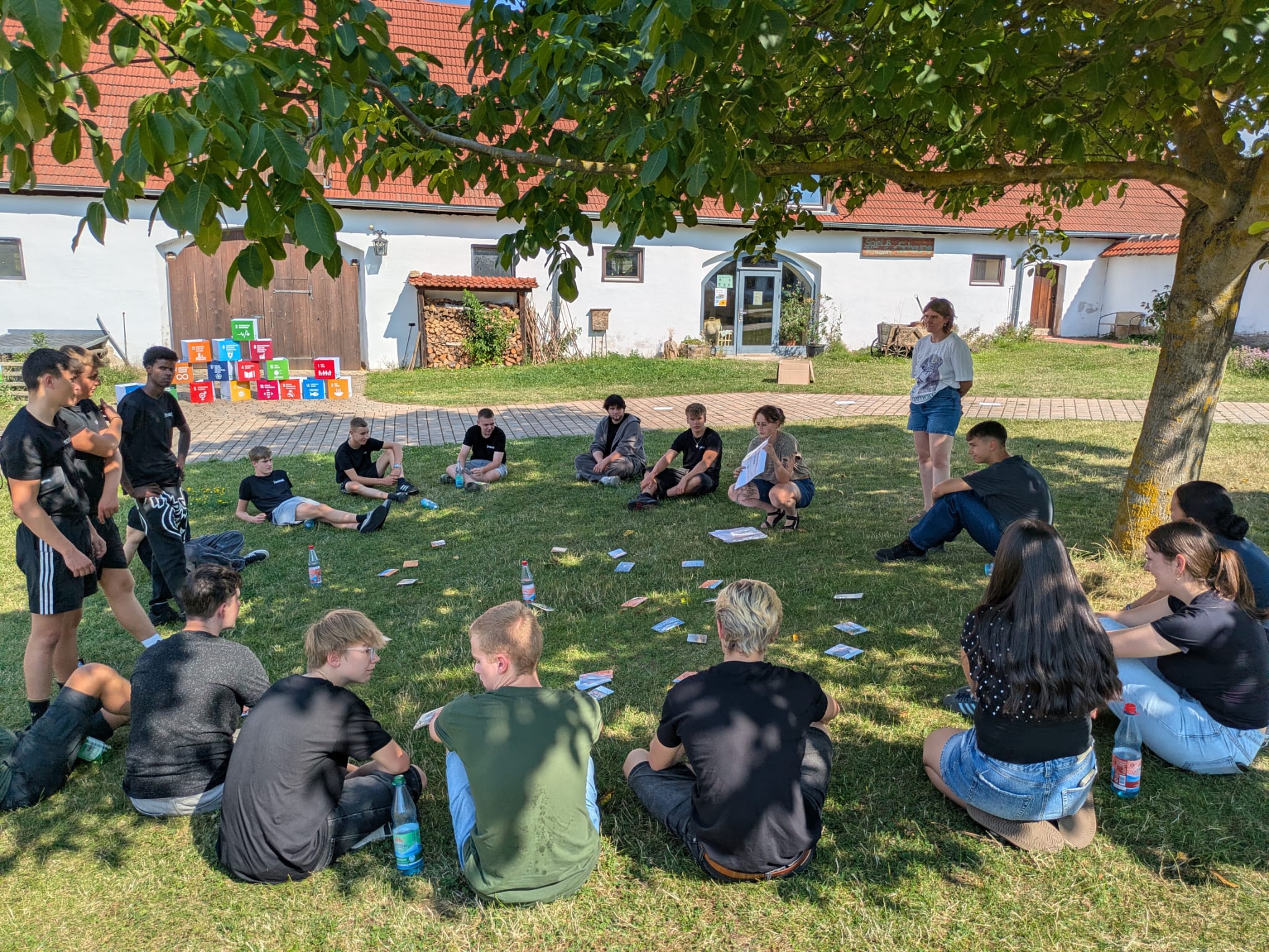 Die neuen Azubis im ersten Lehrjahr vom Autohaus Fischer bei einem Teamspiel auf der Wiese im Sitzen.